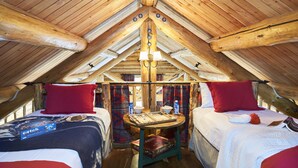 Ein gemütliches Schlafzimmer im Dachgeschoss mit zwei Betten, einer Holzbalkendecke und einem kleinen Tisch mit einem Gesellschaftsspiel.