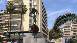 A tall building with multiple balconies and a statue of a figure on a pedestal.
