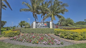 Une enseigne indiquant l’entrée du club nautique et résidentiel ISIA Del Sol, entouré de jardins aménagés et de palmiers.