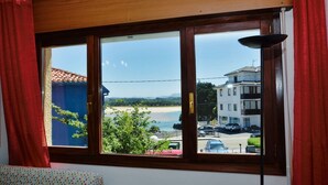 Una habitación con un ventanal grande con vistas a una playa y edificios.