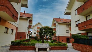Un patio con un banco central, rodeado por edificios de varios pisos con fachadas de ladrillo rojo y tejados de tejas.