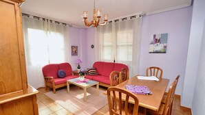 Una sala de estar con un sofá rojo, una mesa de centro de madera y una mesa de comedor con sillas.