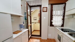 Una cocina compacta con armarios blancos, estufa y lavabo.