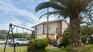 A residential building with a patio area, a swing set, and a palm tree. - Apto con jardín compartido - Villa Cancillo 6802 (Noja)