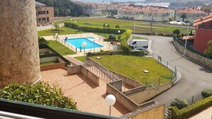 Un barrio residencial con piscina, un pilar de piedra y vista al mar.