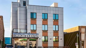Un hotel moderno con fachada de vidrio, varios pisos y un restaurante visible en la planta baja.