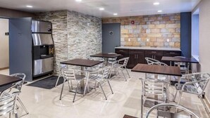 Una cocina moderna con salpicadero de pared de piedra, electrodomésticos de acero inoxidable y una zona de estar con sillas y mesas de metal.