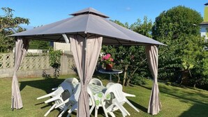 Ein Garten mit einem Pavillon, einem Tisch und Stühlen.