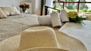 Una stanza accogliente con un'ampia finestra, un letto con biancheria bianca e un cesto di vimini in primo piano.