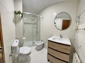 A modern bathroom with a toilet, bidet, and a glass-enclosed shower.