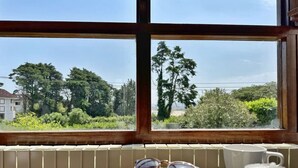 Vista dalla finestra su un giardino con alberi e un edificio sullo sfondo.
