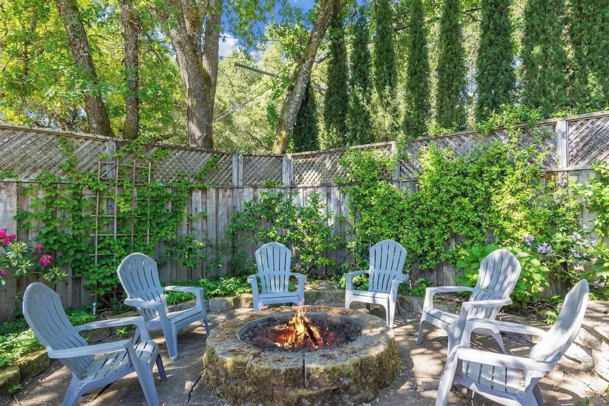 An outdoor seating area with a fire pit surrounded by Adirondack chairs.
