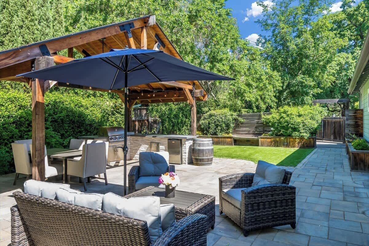 An outdoor patio with wicker furniture, a barbecue grill, and a pergola.