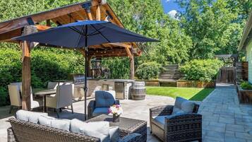 An outdoor patio with wicker furniture, a barbecue grill, and a pergola.