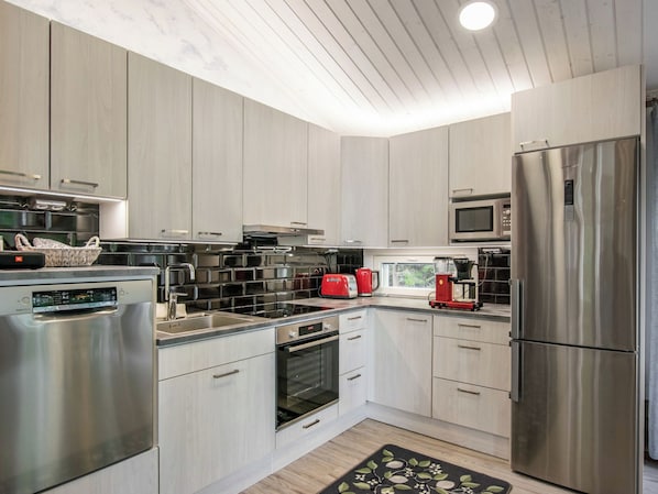 A modern kitchen with stainless steel appliances, a microwave, and a red toaster. - Nummentähti by Interhome (Tammela)