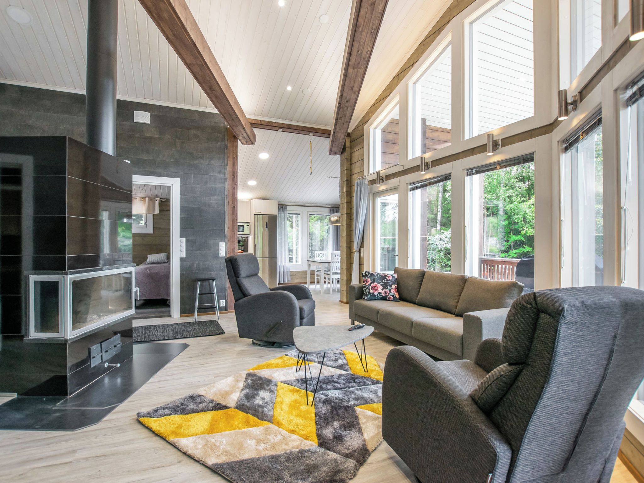 Amplia sala de estar con chimenea, muebles modernos y ventanas grandes que ofrecen vistas al exterior.