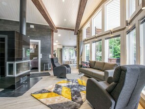 A spacious living area with a fireplace, modern furniture, and large windows offering a view of the outdoors. - Nummentähti by Interhome (Tammela)