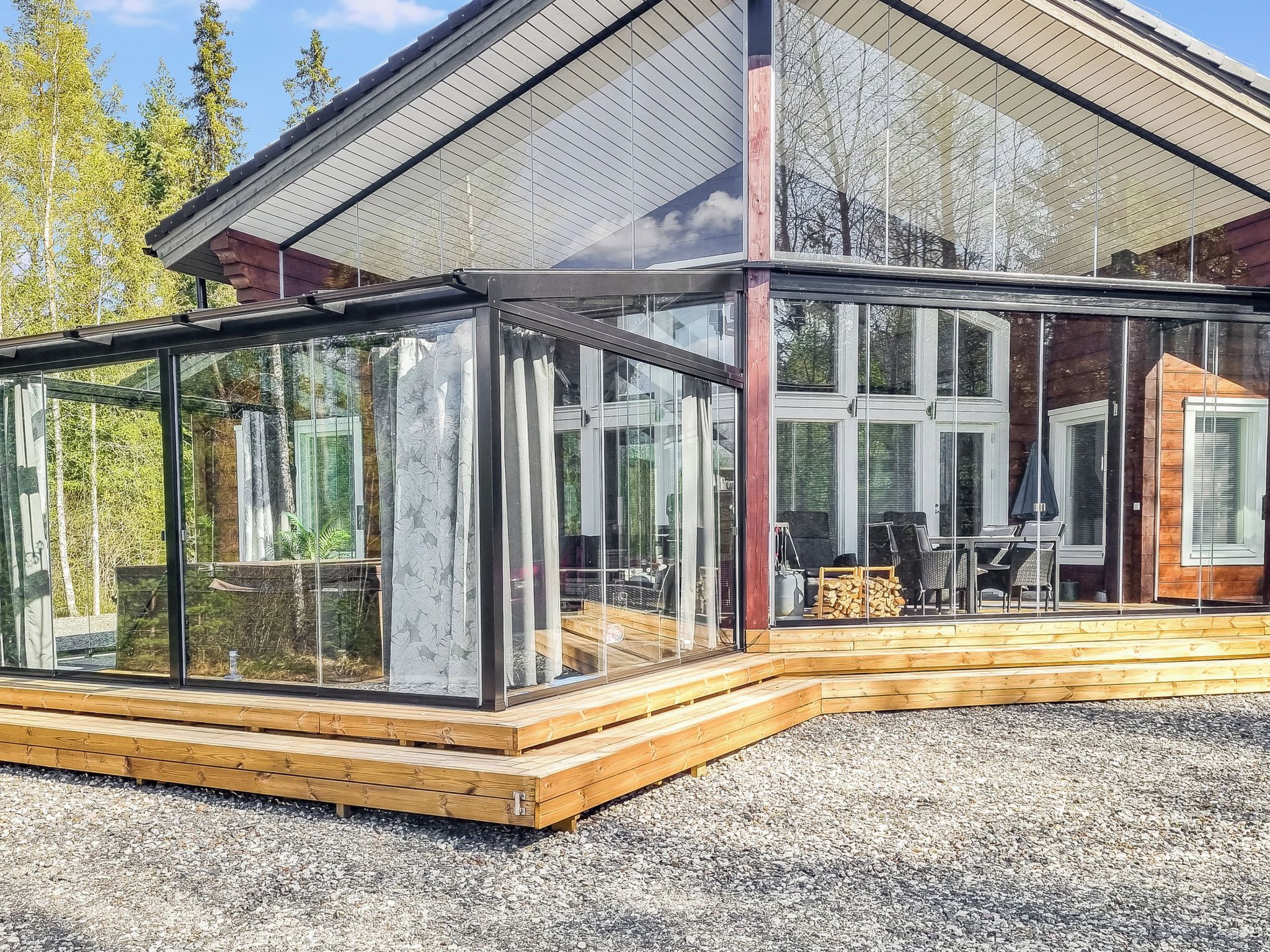 A modern glass-enclosed building with a wooden deck and a covered outdoor area.