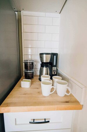 A kitchen counter with a coffee maker, a decaf coffee pot, and several white mugs. - Waterfront • Hot Tub • Beach • Dock • Kayaks (White Stone)