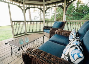 A covered outdoor seating area with wicker furniture and a metal table. - Waterfront • Hot Tub • Beach • Dock • Kayaks (White Stone)