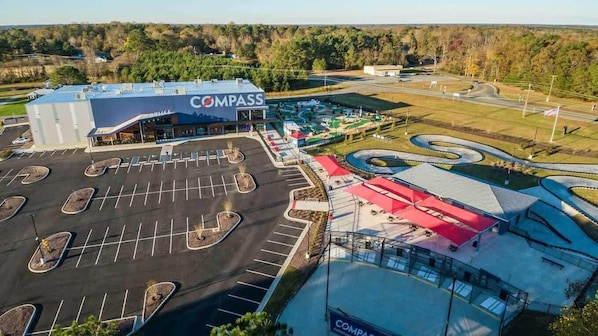 A Compass store with a parking lot, outdoor seating, and a landscaped area with winding paths.