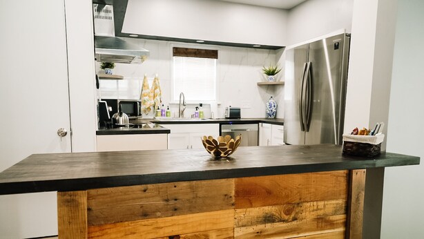Une cuisine moderne avec un îlot central en bois, des appareils électroménagers en acier inoxydable et des meubles de rangement blancs.
