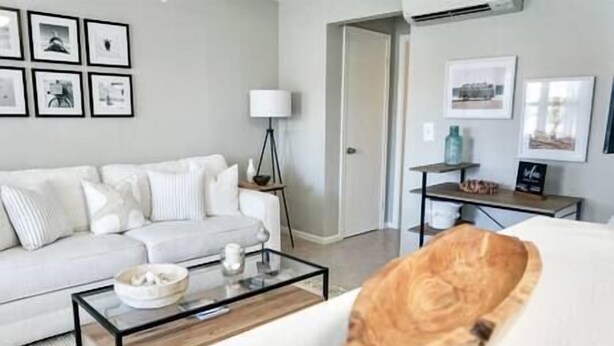 Un salon moderne avec un canapé blanc, une table basse en verre et une grande fenêtre.