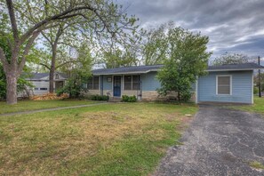 A single-story house with a front porch, a driveway, and a lawn.