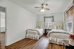 Un dormitorio con dos camas, un ventilador de techo y una ventana con persianas.