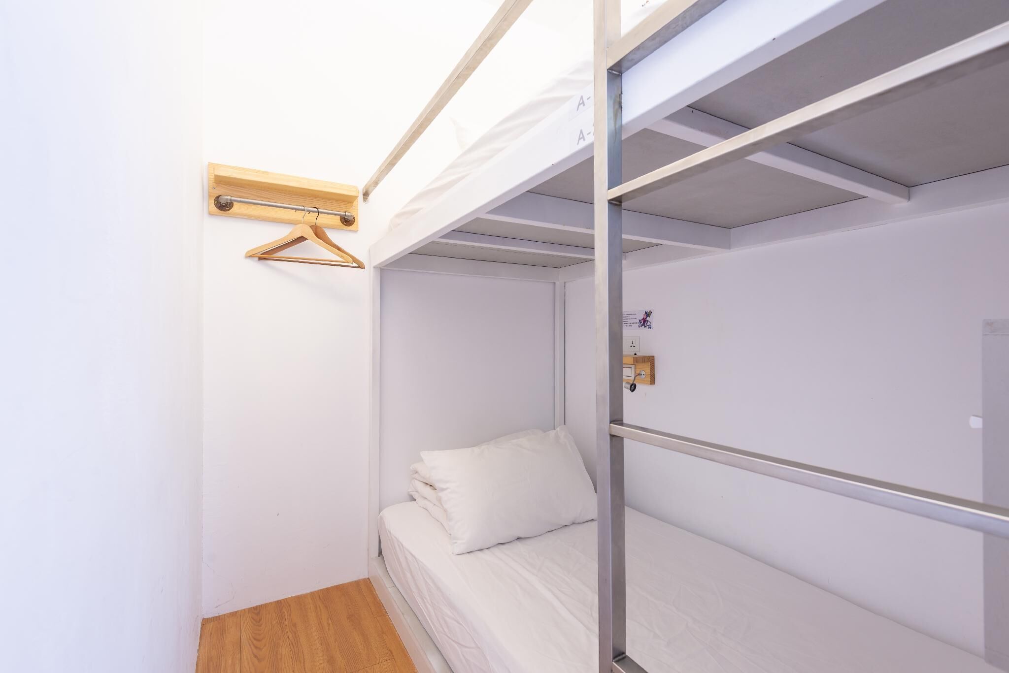 A bunk bed room with a wooden hanger and a small shelf.