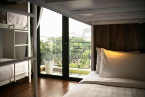 A room with a bunk bed, a desk, and a large window with a view of greenery. - Hanoi Backpacker Suite Hostel (Hanoi)