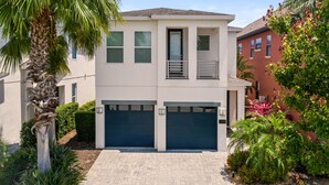 A two-story house with a front garage, a balcony, and a well-maintained garden.