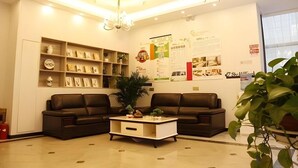 A reception area with a modern design, featuring two sofas, a coffee table, and a large potted plant. - Shell Nanjing Yuhuatai District Meishan Town Wanghai Pedestrian Street Hotel (Nanjing)