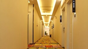 A hotel hallway with a patterned carpet, overhead lighting, and doors with room numbers. - Shell Nanjing Yuhuatai District Meishan Town Wanghai Pedestrian Street Hotel (Nanjing)