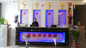 A hotel reception area with a receptionist, a digital display board, and a chandelier. - Shell Nanjing Yuhuatai District Meishan Town Wanghai Pedestrian Street Hotel (Nanjing)