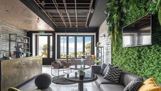 Un espace de détente moderne avec un canapé, des tables rondes et un mur végétal.