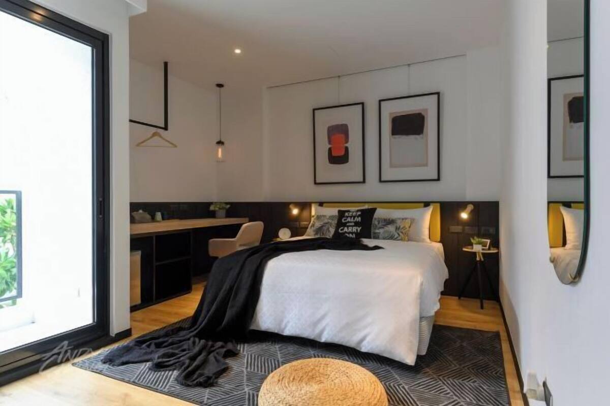 Un dormitorio moderno con una cama grande, un escritorio y una lámpara colgante.