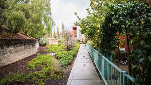 Un sendero bordeado de vegetación y un edificio rojo al fondo.