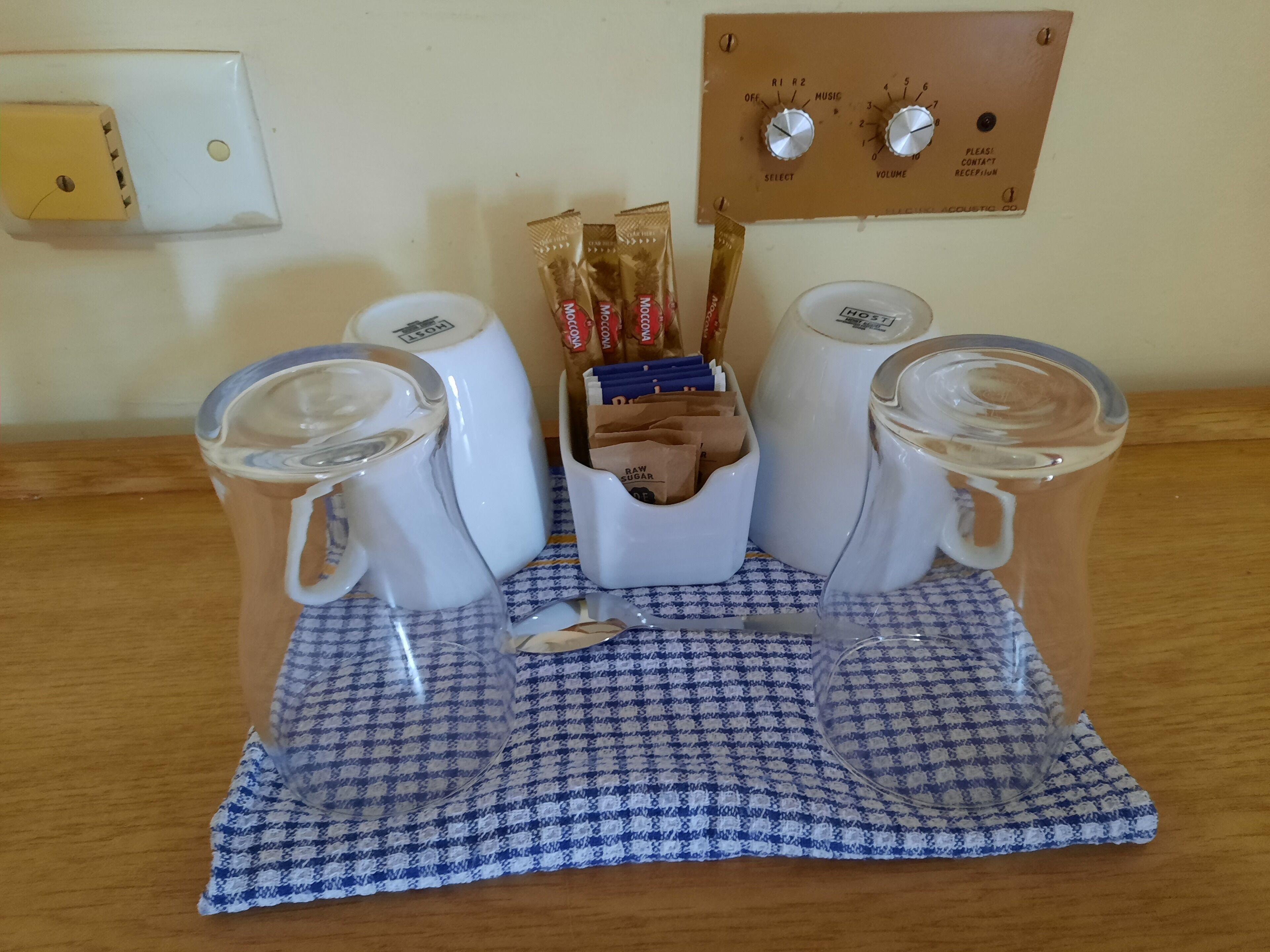 A table with four mugs, a tissue box, and a tissue roll.