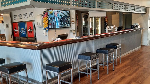 A bar area with a counter, bar stools, and a television screen.