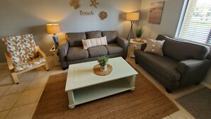 Una sala de estar con dos sofás, una mesa de centro y una lámpara.