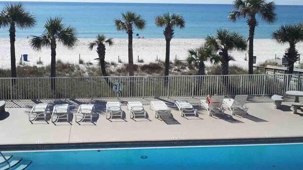 Zona junto a la piscina con sillones de descanso y vista a la playa.