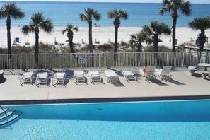 Relax by the pool surrounded by palm trees and a sandy beach.