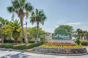 Welcome to Gulf Highlands Beach Resort, where lush landscaping and palm trees frame the entrance.