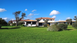 A two-story building with a red-tiled roof, surrounded by a well-maintained lawn and trees. - Gran Torre Hotel (Cabras)