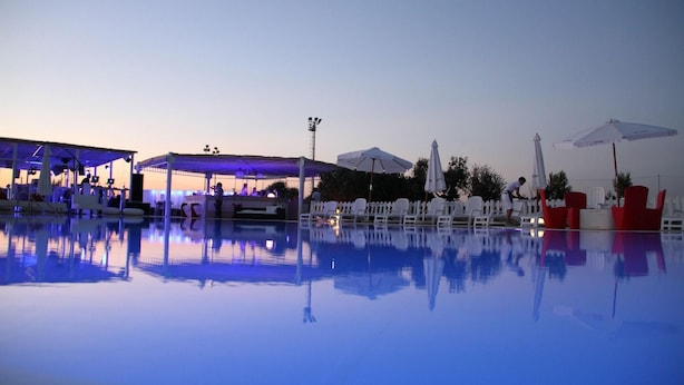 A pool area with lounge chairs and umbrellas, a covered seating area, and a fence. - Gran Torre Hotel (Cabras)