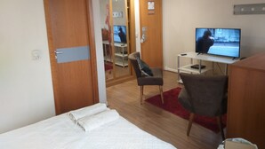 Une chambre d’hôtel comprenant un lit, un bureau avec une télévision, une chaise et une armoire.