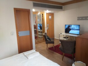 Ett hotellrum med en säng, ett skrivbord med en tv, en stol och en garderob.