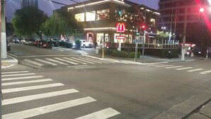 Un restaurant McDonald's de nuit, avec un passage piéton et des voitures garées.