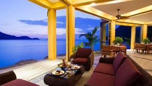 A spacious indoor area with a view of the sea, furnished with a sofa, chairs, and a dining table. - Siam Royal View Resort Apartments (Koh Chang)